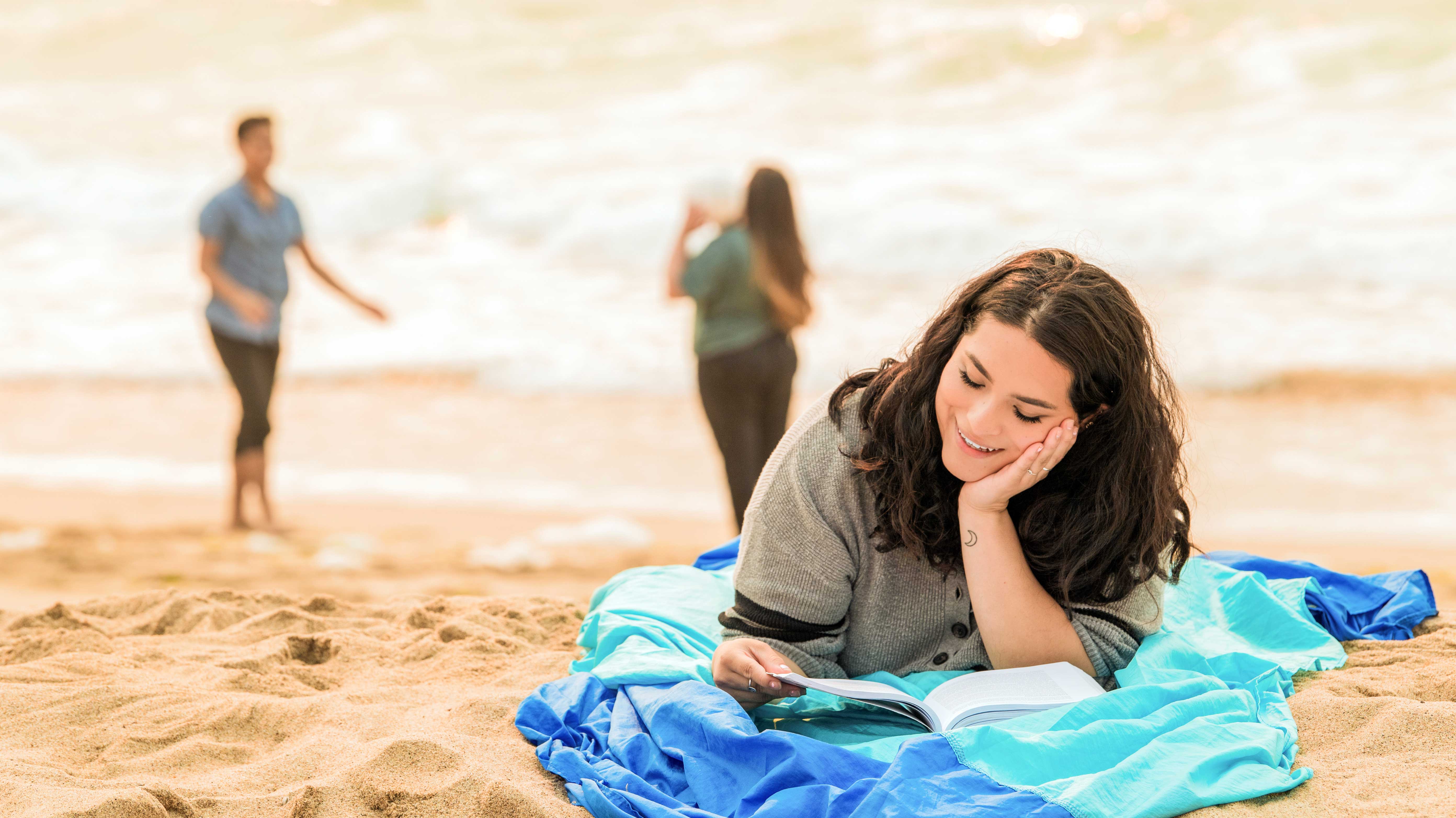 student laying on the beach reading