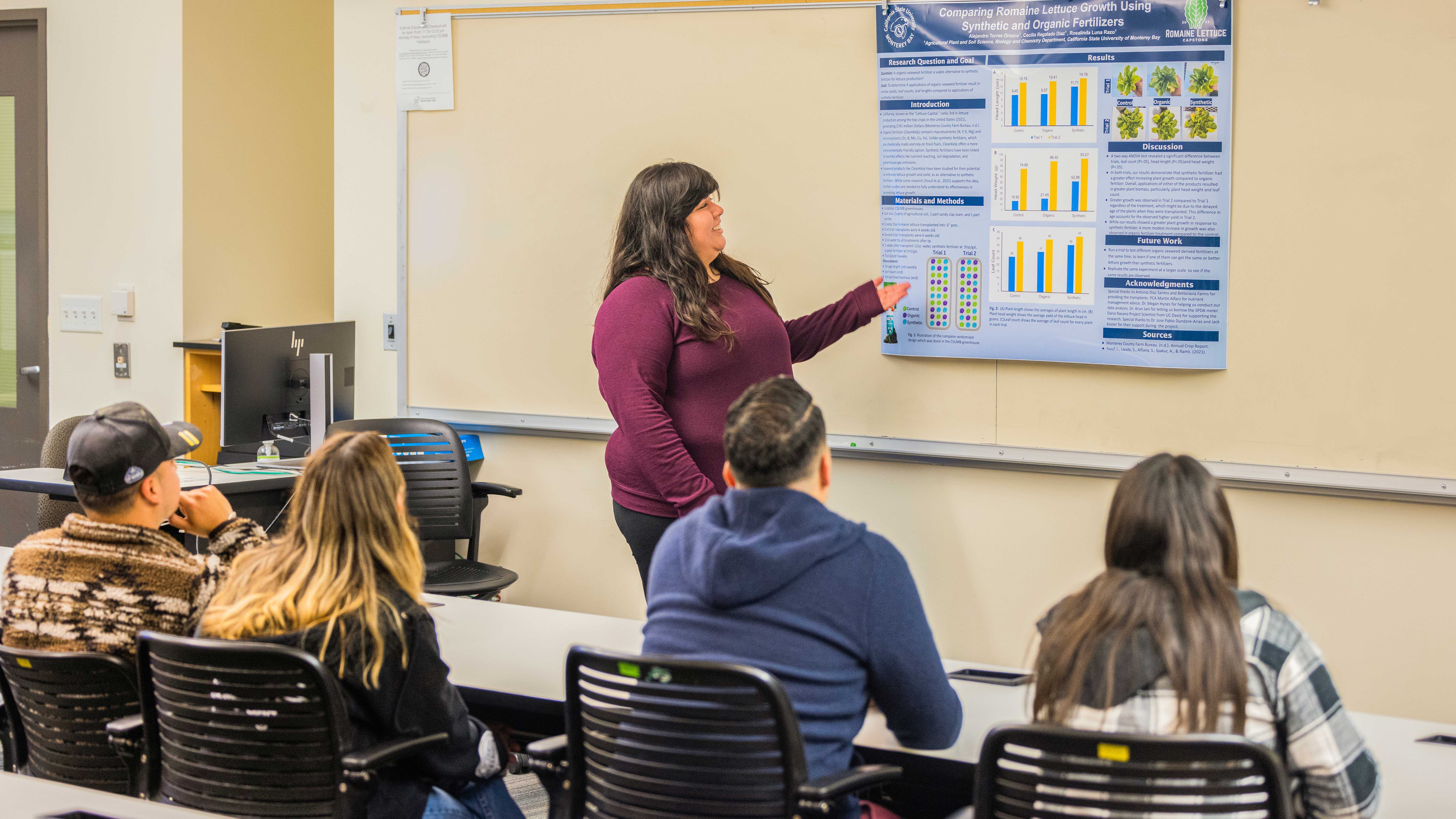 students and a professor in a classroom looking at a white board