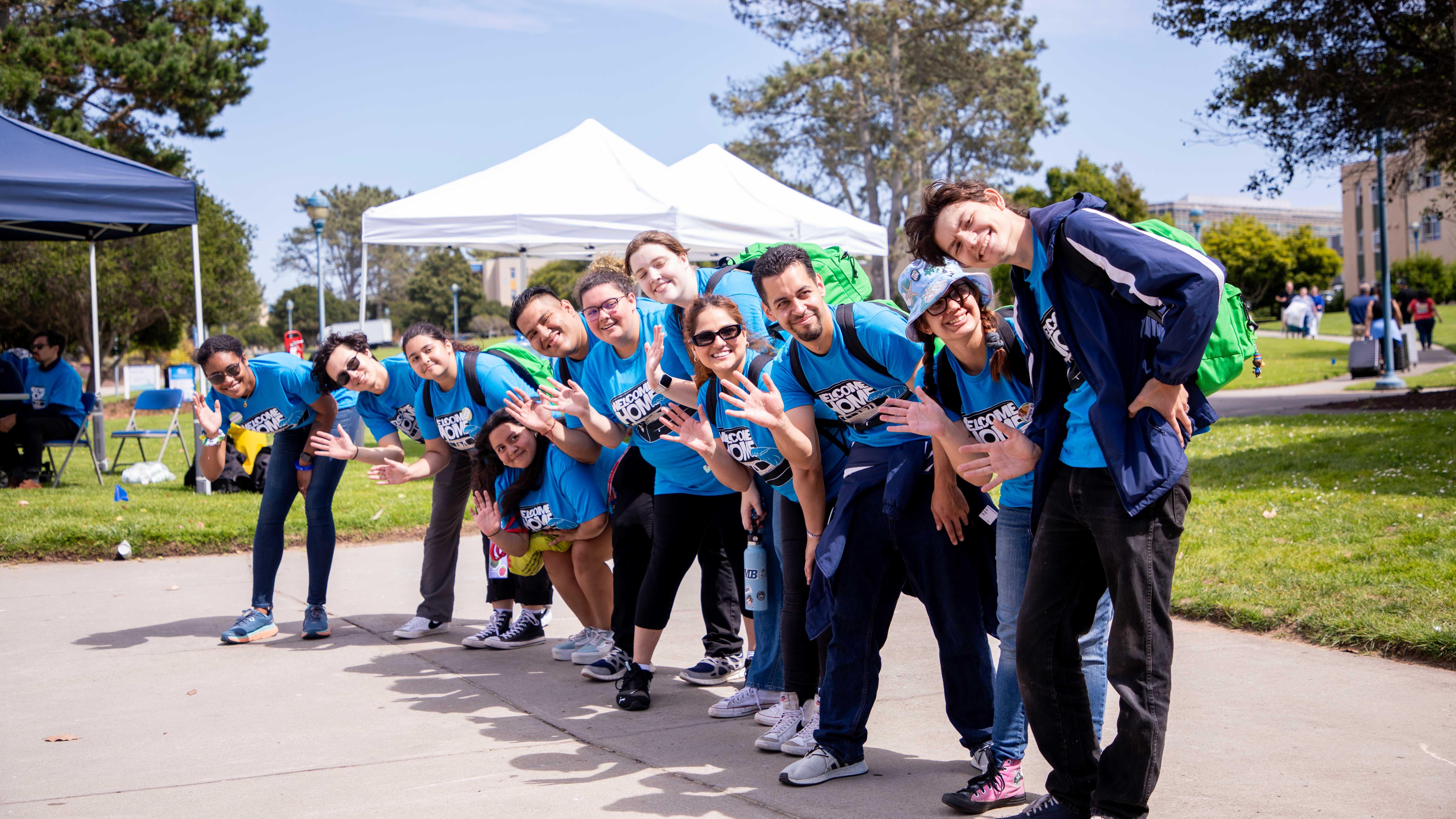 students  in a matching blue t shirts waving at the camera