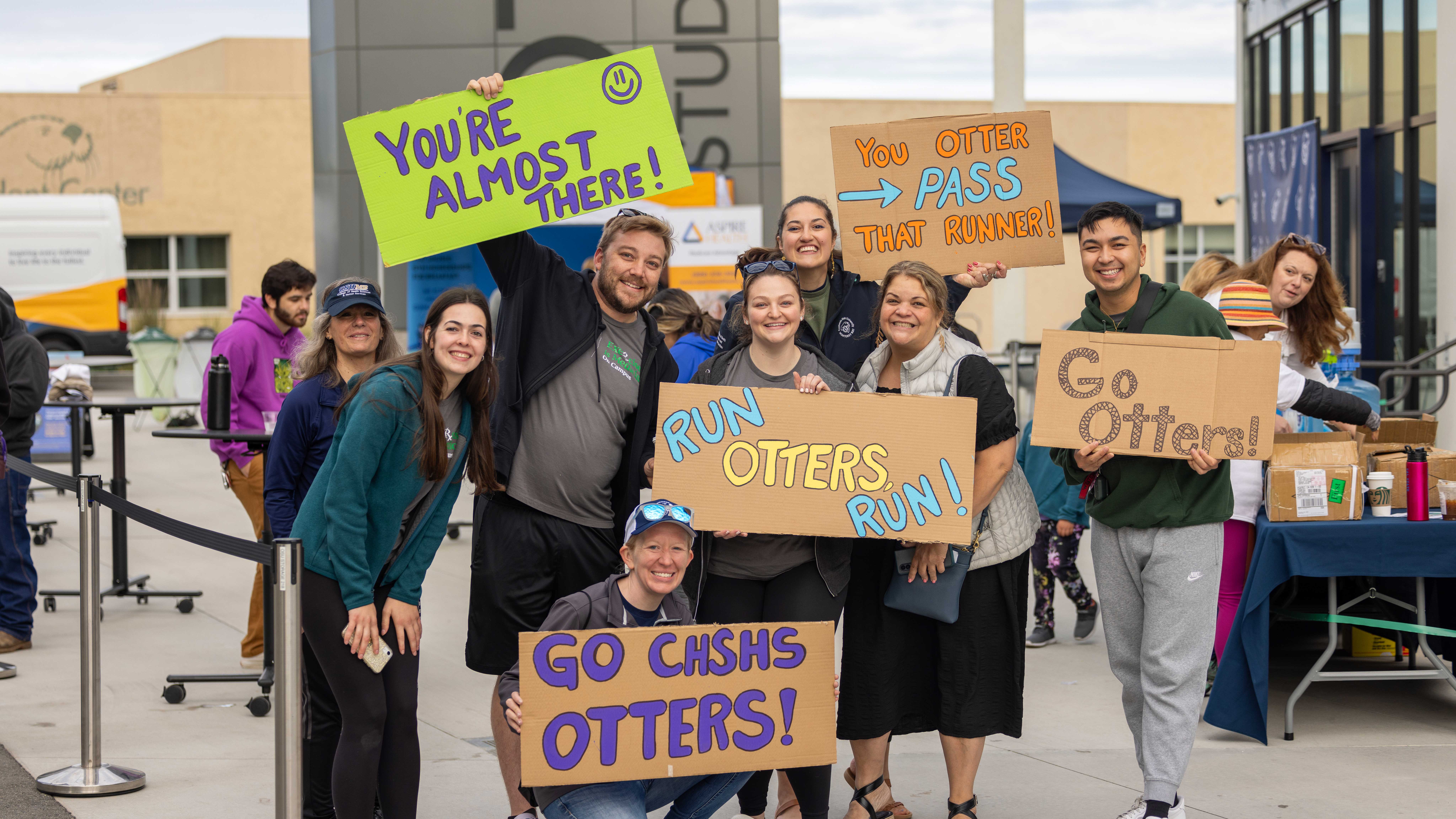 people holding signs "Go CHSHS Otters" and "Run Otters Run" and "Go Otters" 