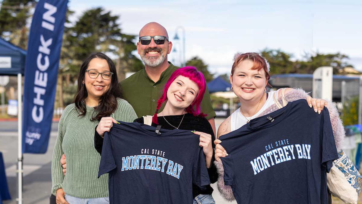 two students and parents smiling and holding CSUMB t shirts